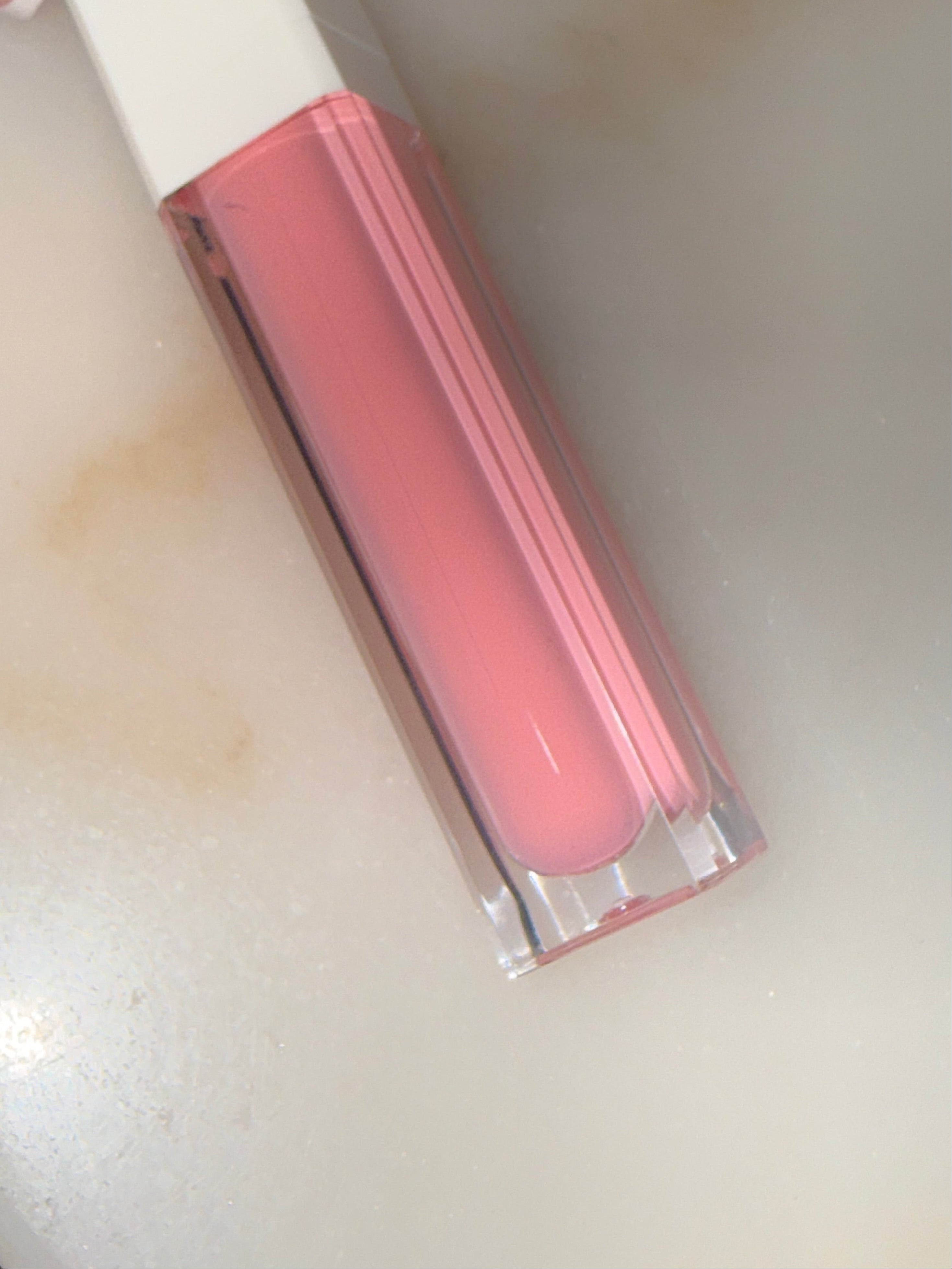 Pink lip gloss on a white surface